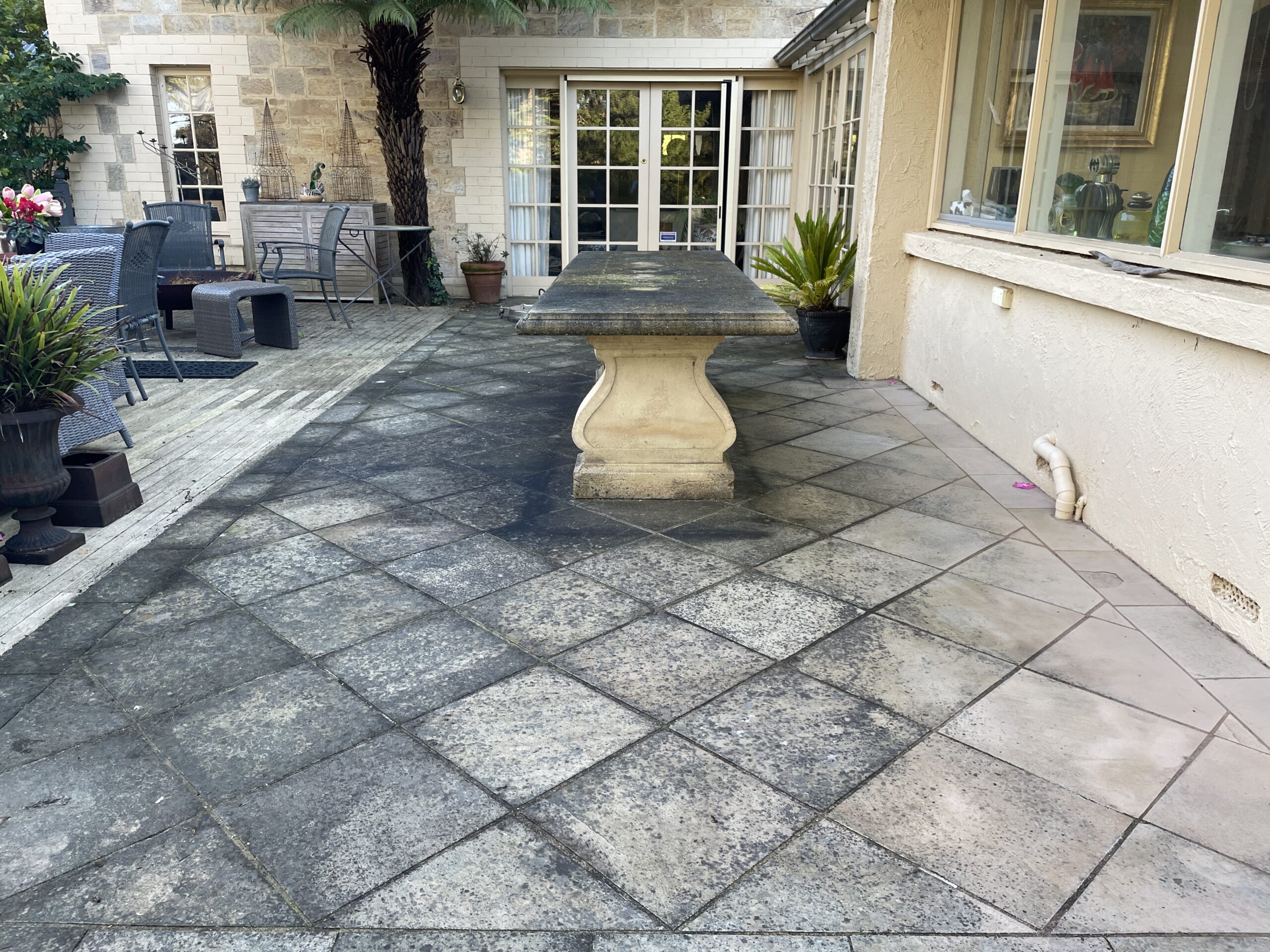 Outdoor area with stone tiles and furniture in need of surface restoration.