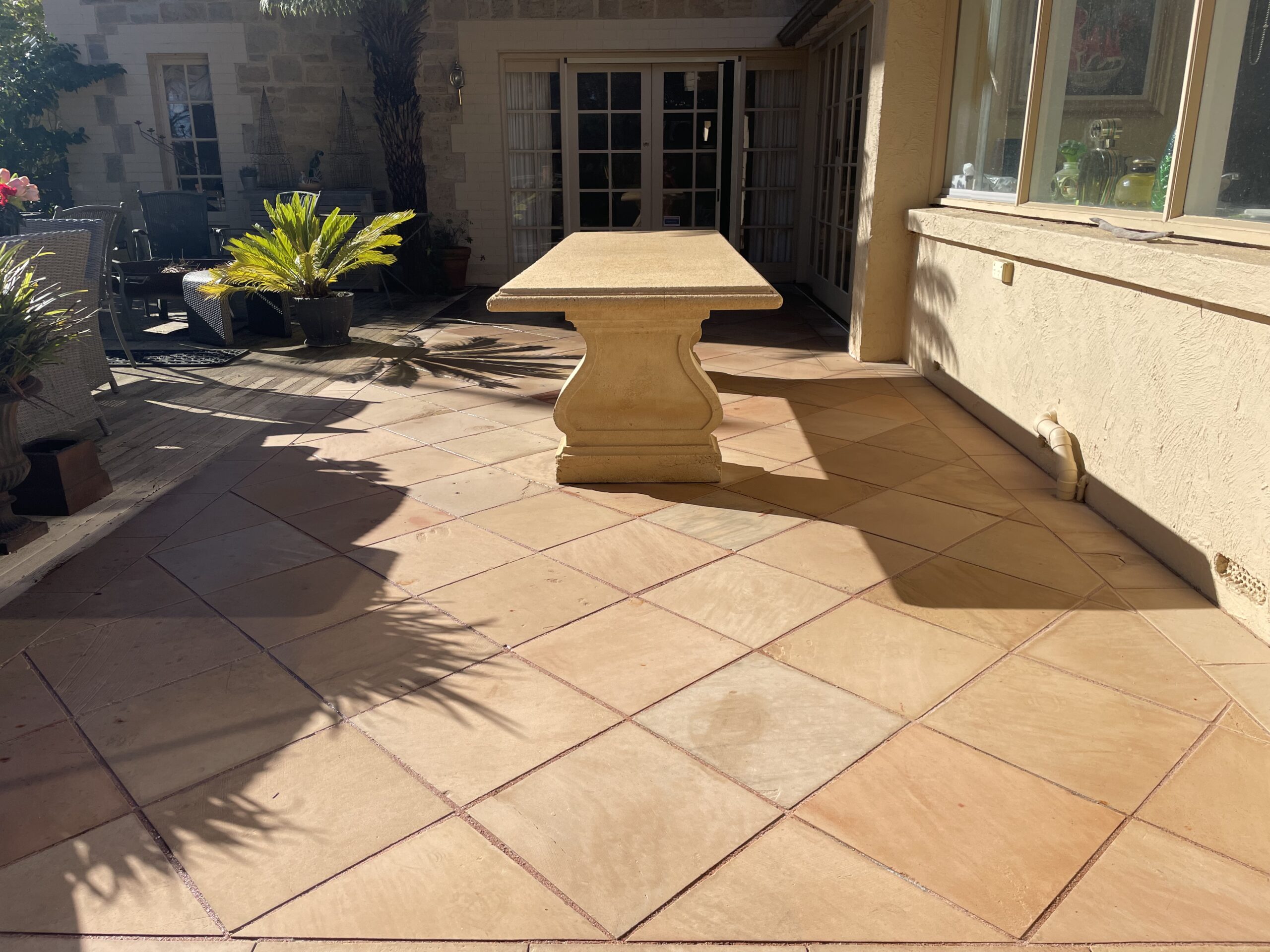 Sunlit patio with elegant paving and decorative outdoor furniture in Adelaide.