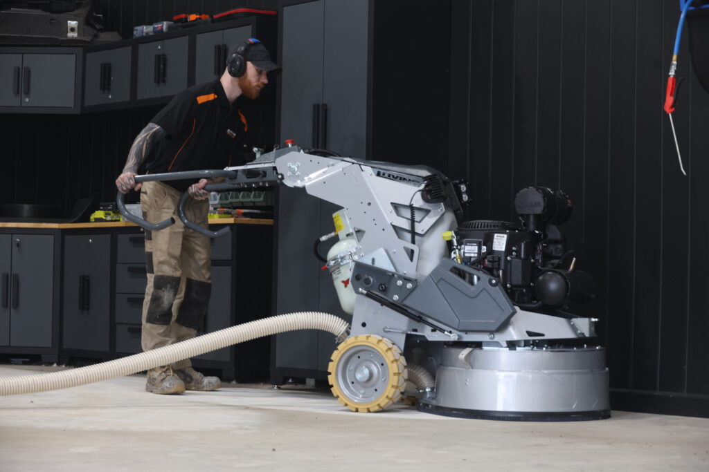 Worker using floor resurfacing machine in a professional workshop.