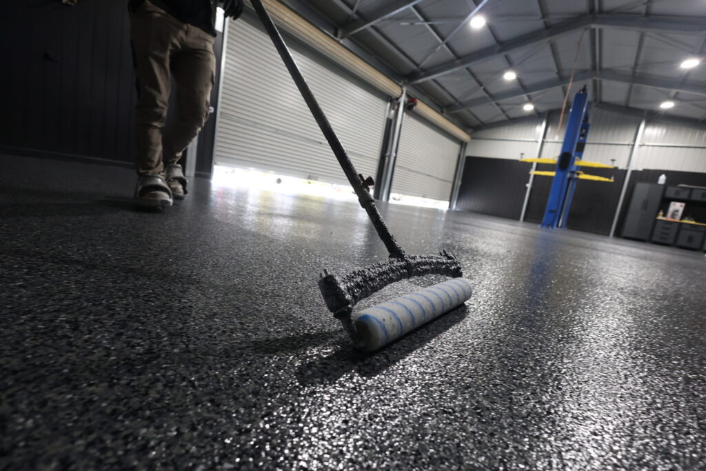 Worker applying a fresh coat on a garage floor in Adelaide.