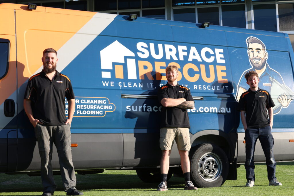 Three men standing by a Surface Rescue service van on a sunny day.