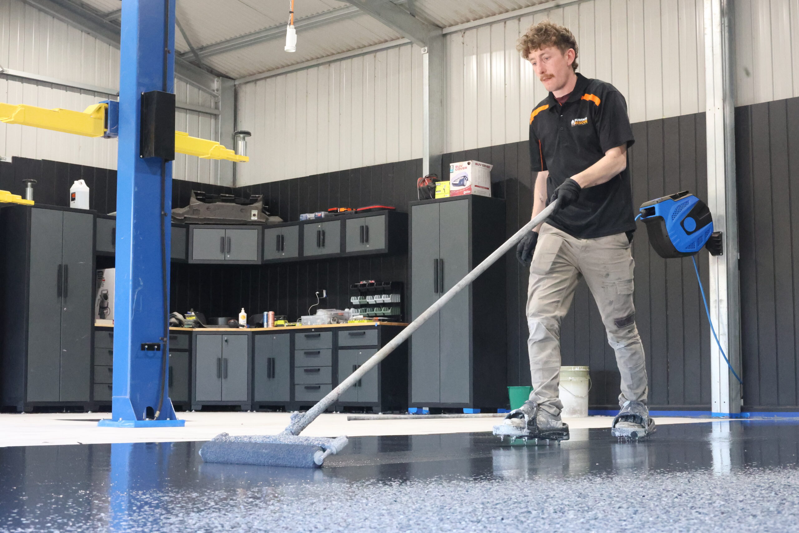 Professional epoxy flooring application in an Australian garage using roller for a smooth, long-lasting finish