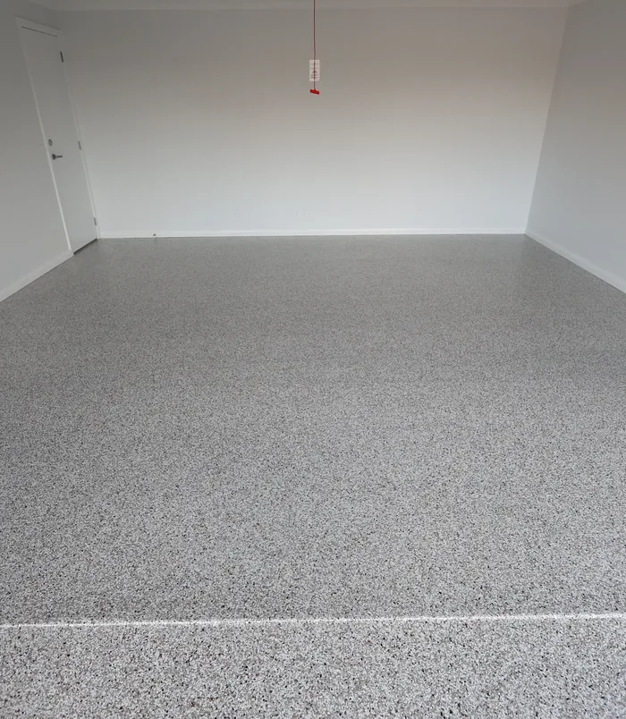 Grey speckled epoxy flake floor in an empty room with white walls