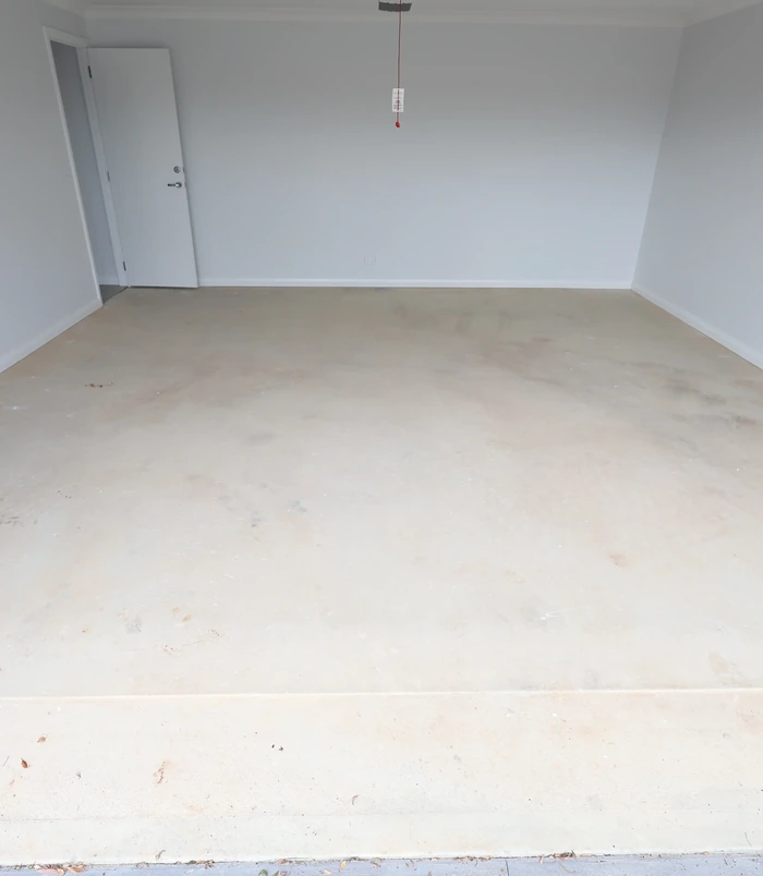 Plain concrete floor in an empty room with white walls, before epoxy flooring