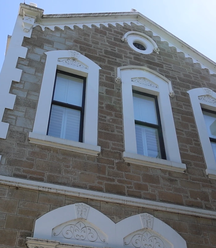Heritage sandstone and brick building with arched windows, dull and weathered, before pressure washing