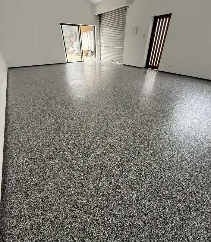 Glossy grey epoxy flake floor in an empty room with glass doors