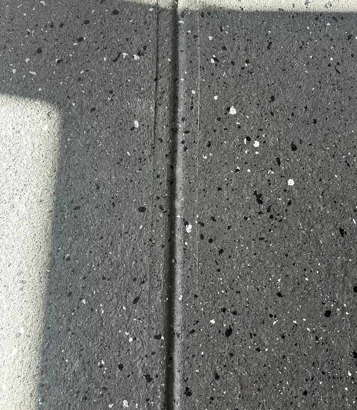Close-up of dark speckled resurfaced concrete with a clean joint line
