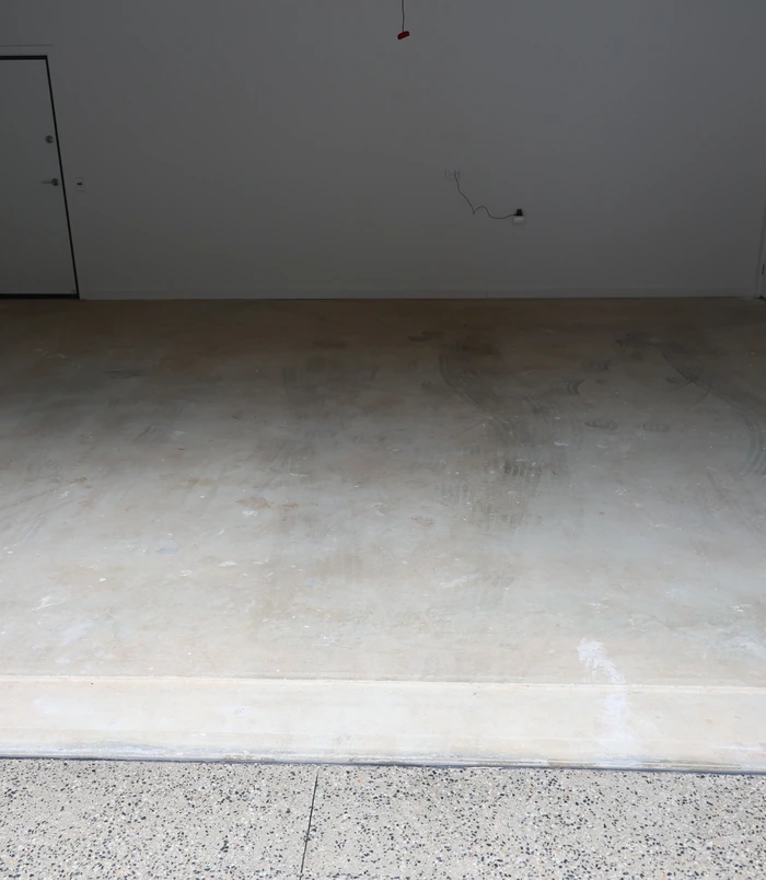 Dark, bare concrete floor in a dimly lit room, before epoxy flooring