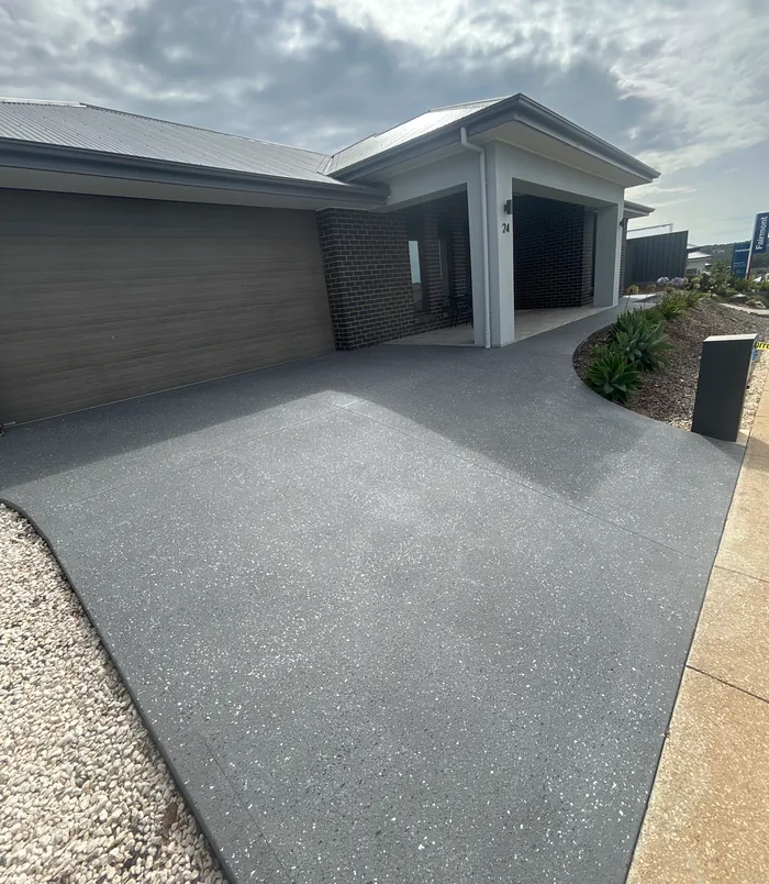 Dark grey resurfaced concrete driveway in front of a modern home with a double garage