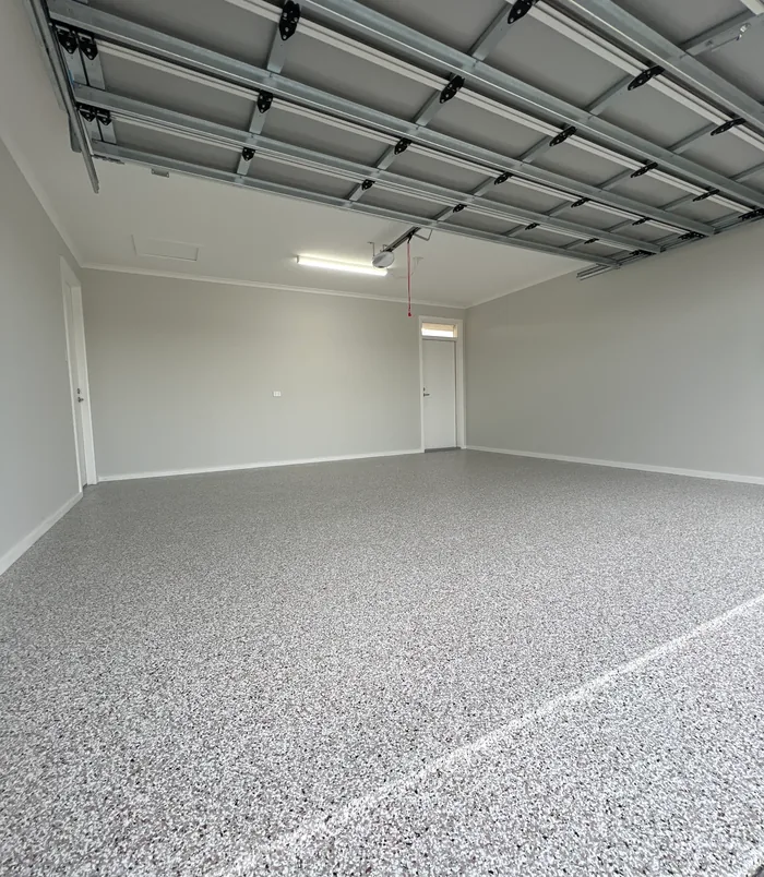 Smooth grey epoxy garage floor with white walls and a roller door