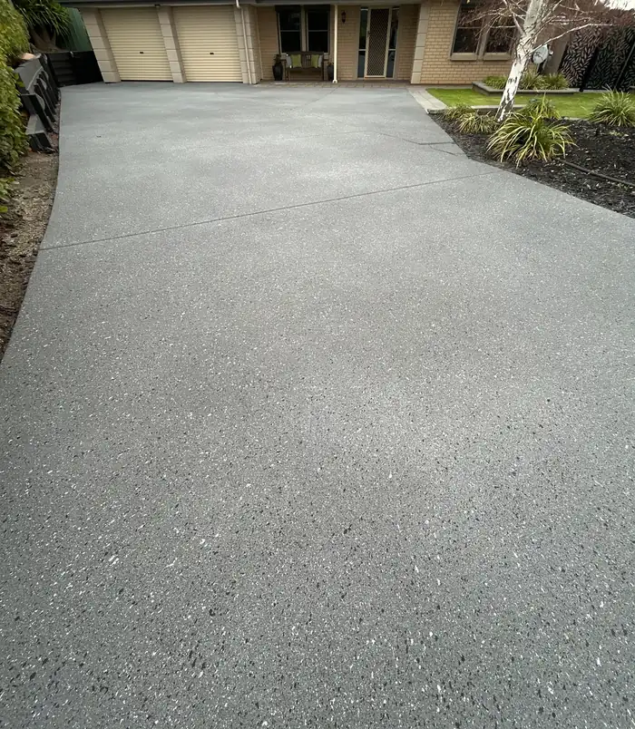Clean, even grey resurfaced concrete driveway leading to a garage