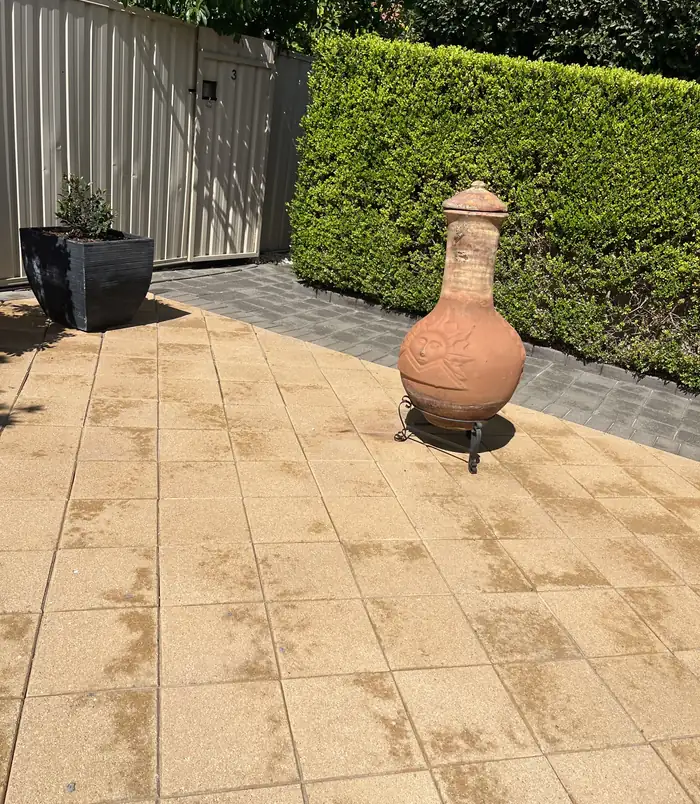 Clean, golden patio pavers with a terracotta chiminea and planter pots after pressure washing