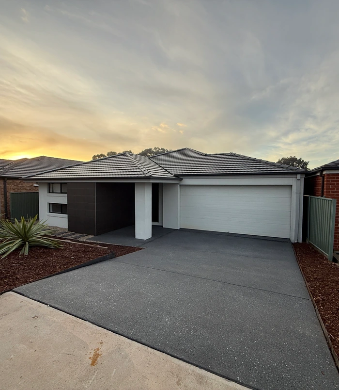 Resurfaced concrete driveway in front of a home with a white garage door at dusk