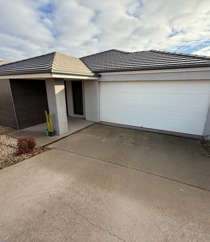 Faded concrete driveway in front of a garage with a white door, before concrete resurfacing