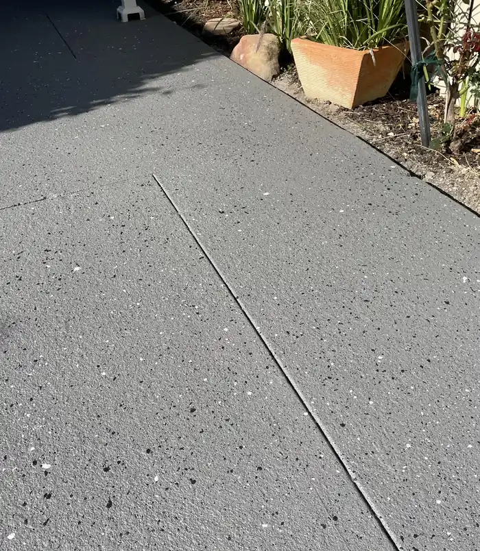 Smooth, dark grey resurfaced concrete slab beside garden pots with no visible cracks