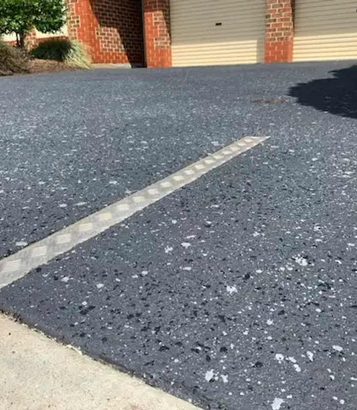 Dark speckled resurfaced concrete with a drainage strip across it
