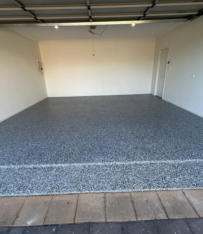 Empty garage with a dark blue-grey speckled epoxy flake floor