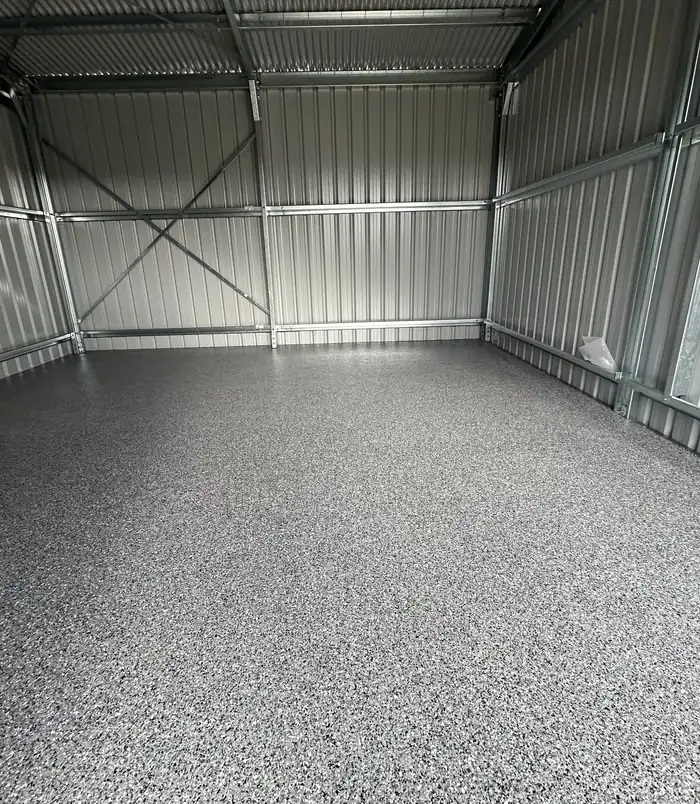 Dark speckled epoxy flake floor in a large empty metal shed