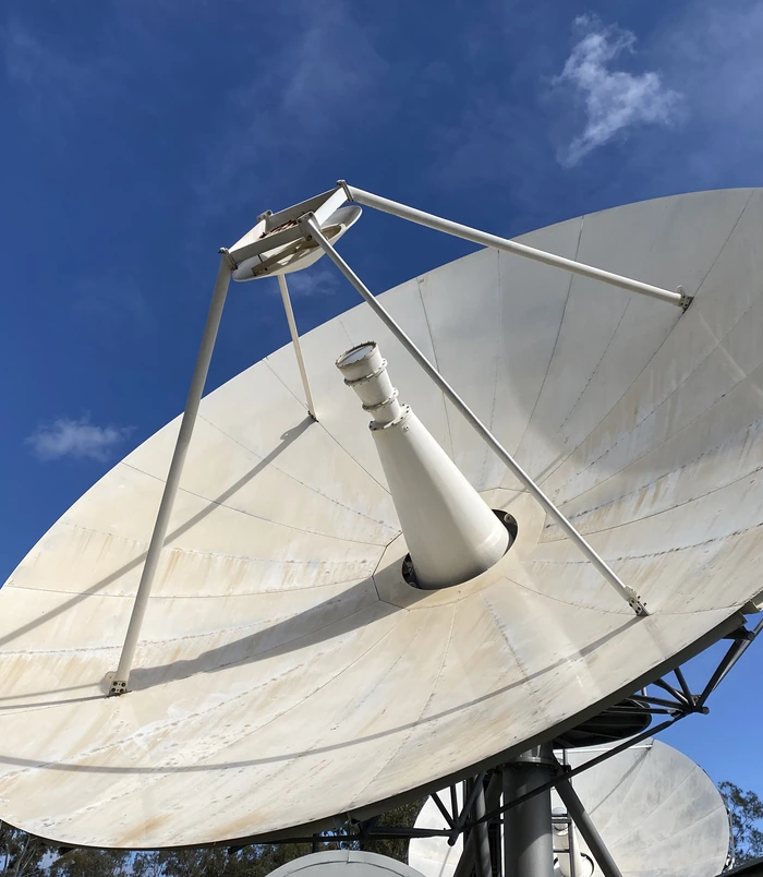 Clean white satellite dish against a blue sky after pressure washing