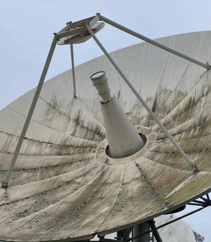 Satellite dish with green algae and grime streaks on its surface, before pressure washing