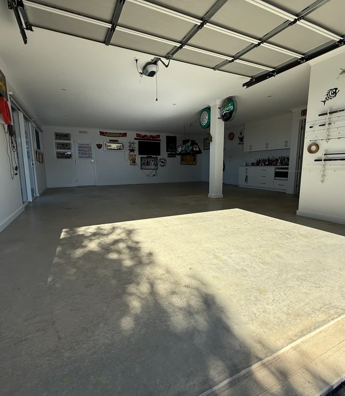 Dull concrete garage floor in a workshop with memorabilia on the walls, before epoxy flooring