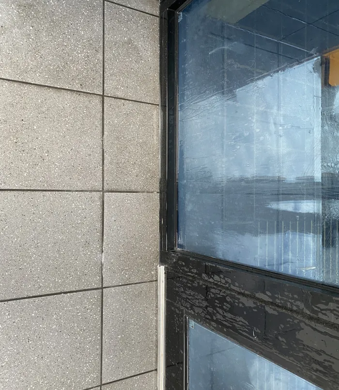Clean concrete panel wall beside a window with graffiti removed