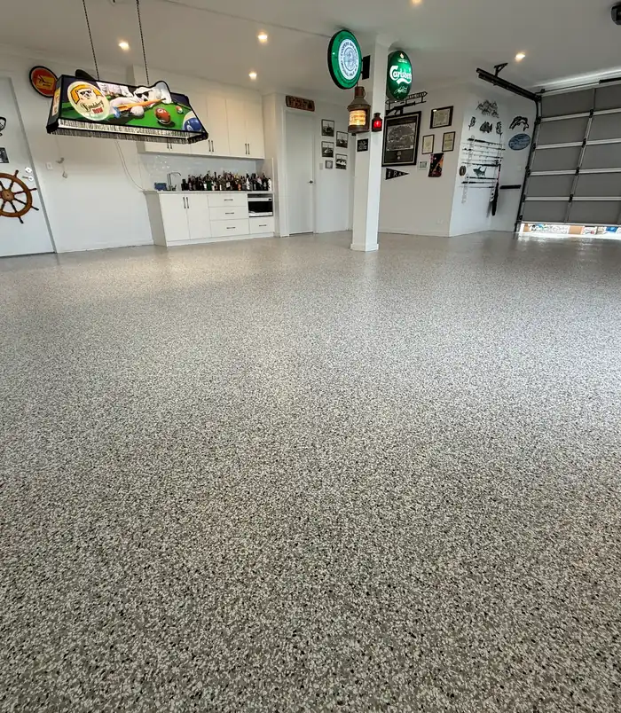 Speckled epoxy flake garage floor in a workshop with a bar sign and memorabilia