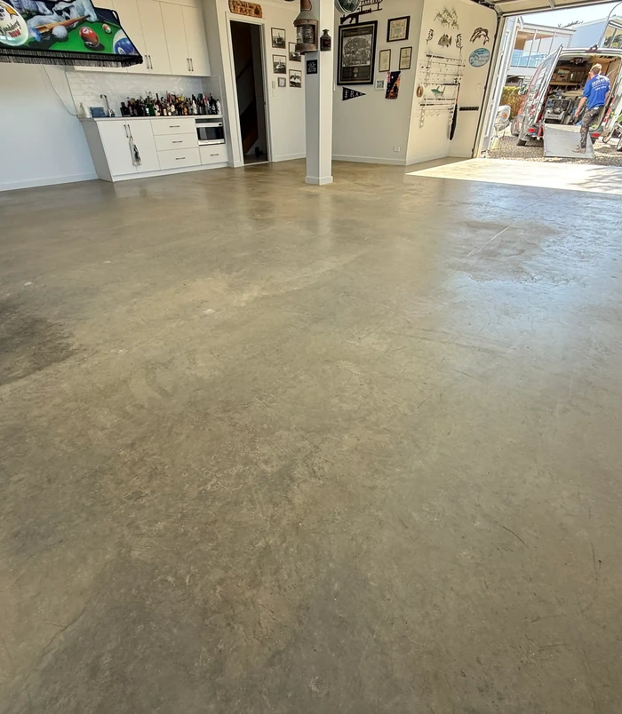 Stained, uneven concrete workshop floor with cabinets along the wall, before epoxy flooring