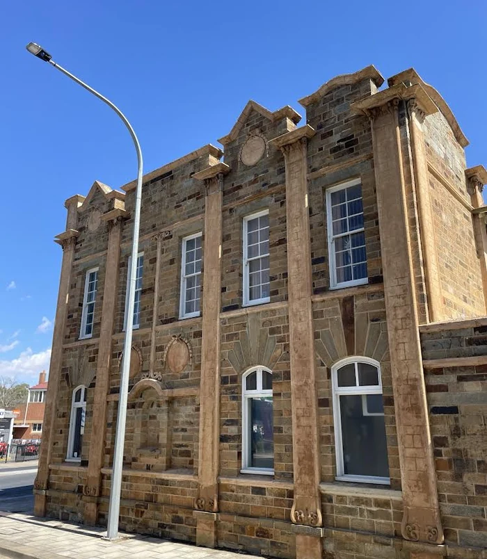 Heritage sandstone building with clean, warm-toned stonework under a blue sky after pressure washing