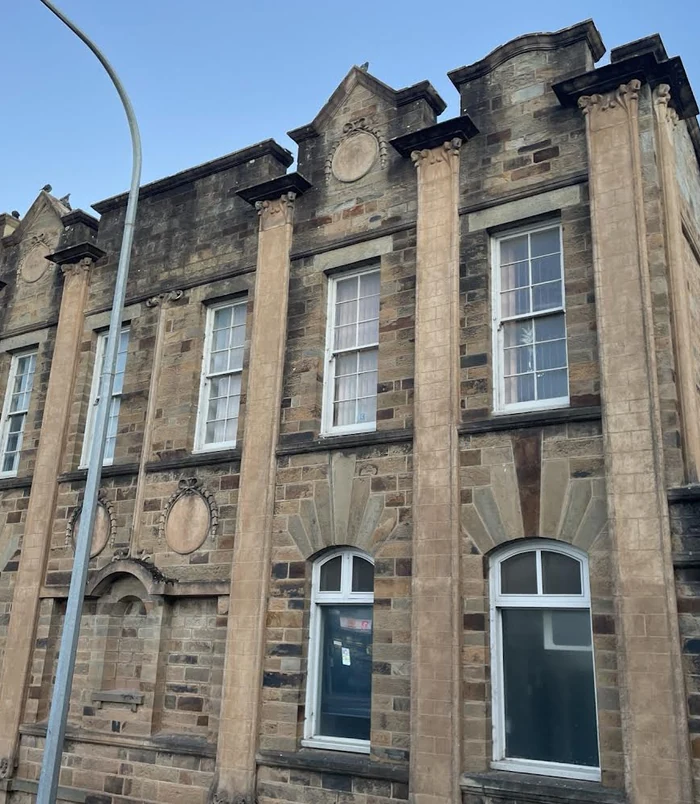 Heritage sandstone building with dark, weathered stonework and grime, before pressure washing