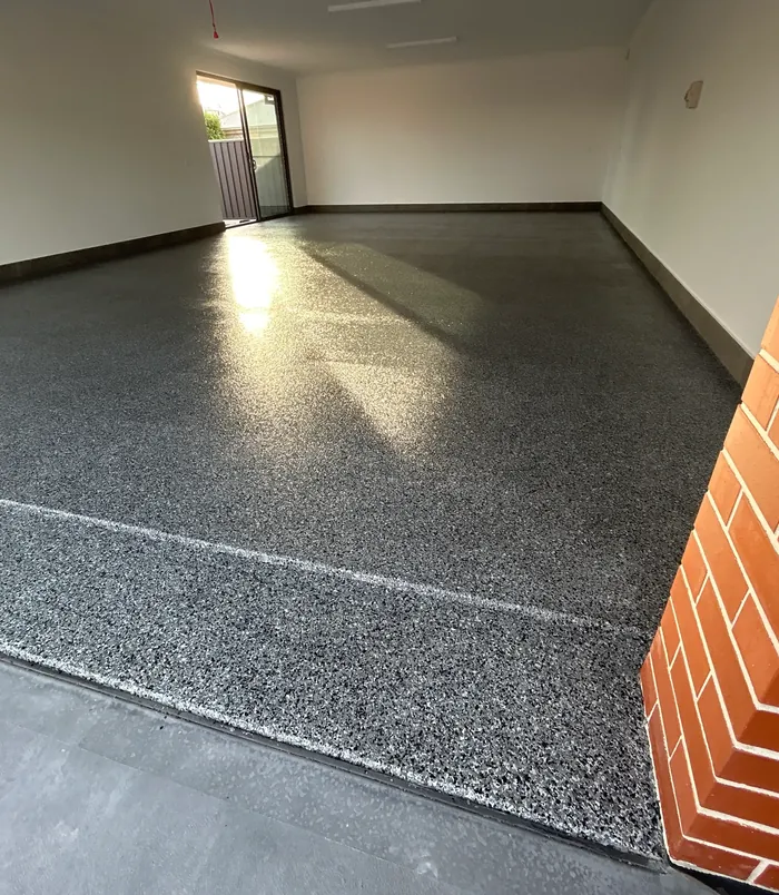 Dark speckled epoxy flake floor with a glossy finish in a large empty room