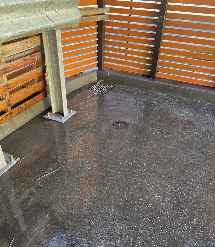 Clean, damp concrete floor in an enclosed area with timber slat screens after pressure washing