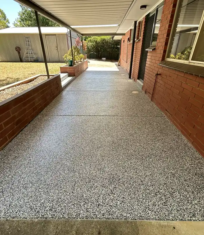 Speckled epoxy flake veranda floor beside a brick wall and garden bed