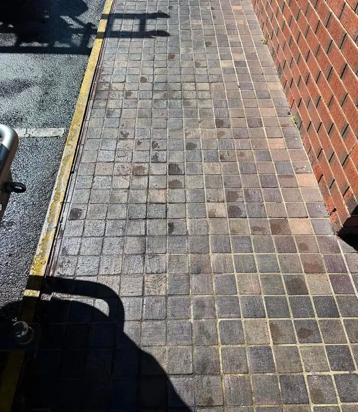 Clean tiled path beside a brick wall with a restored, even colour after pressure washing