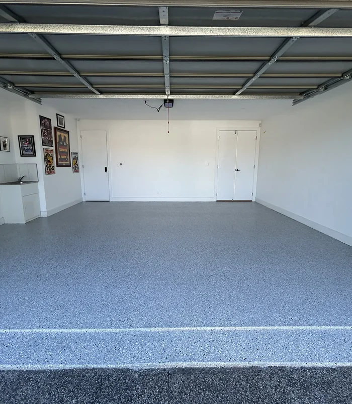 Glossy grey epoxy flake garage floor with framed memorabilia on the walls