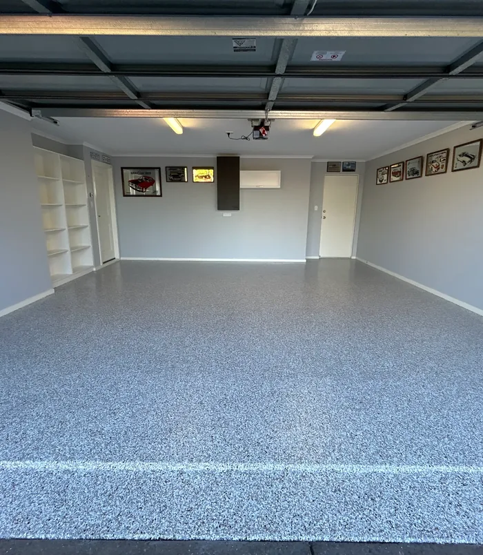 Glossy grey epoxy flake floor in a garage with built-in shelving and wall displays