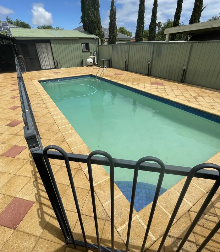 Clean, golden patterned paving in a backyard beside a house after pressure washing