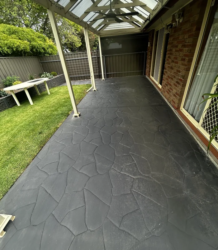 Dark grey resurfaced stamped-pattern concrete patio with a refreshed, even finish