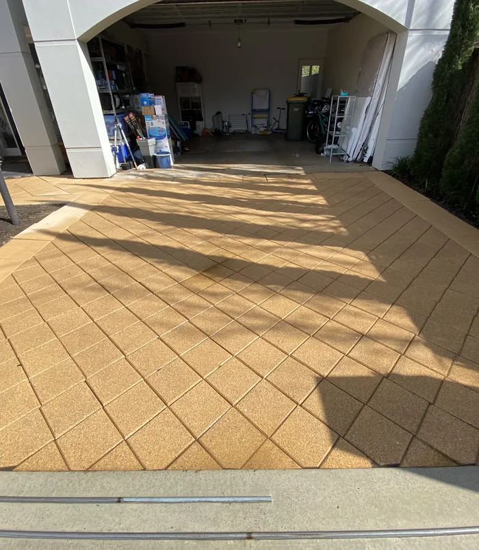 Clean, warm-toned concrete driveway leading into a garage after pressure washing