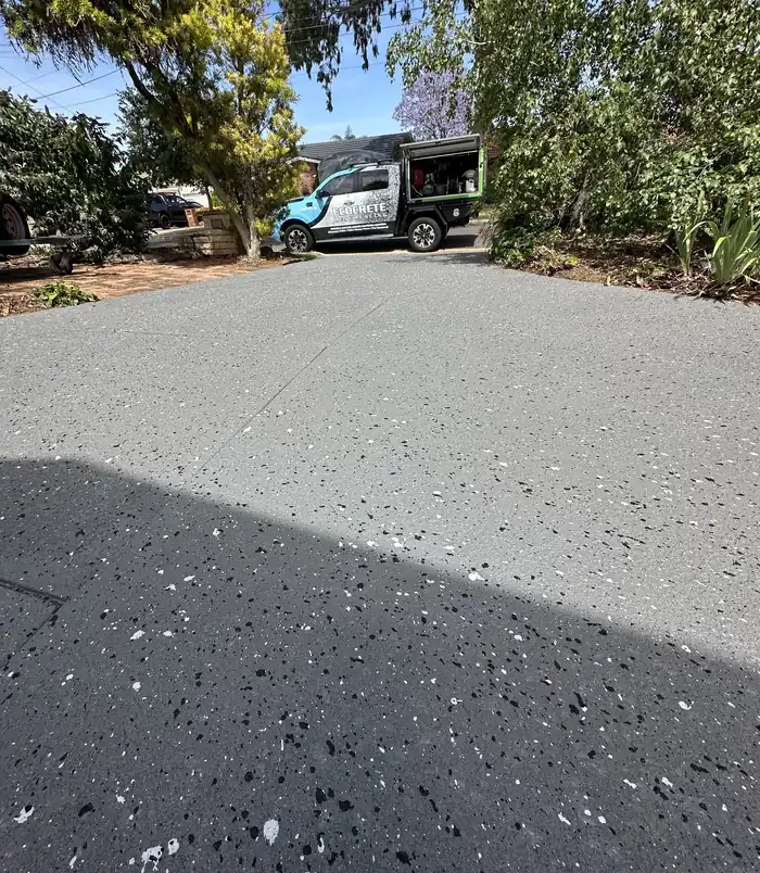 Dark speckled resurfaced concrete driveway with a clean, even finish