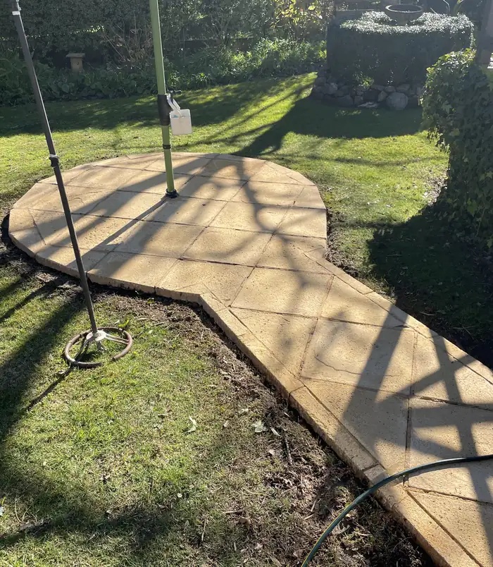 Clean, golden stone patio circle set in a lawn after pressure washing