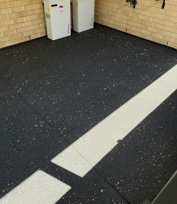 Dark speckled resurfaced concrete courtyard beside a brick wall