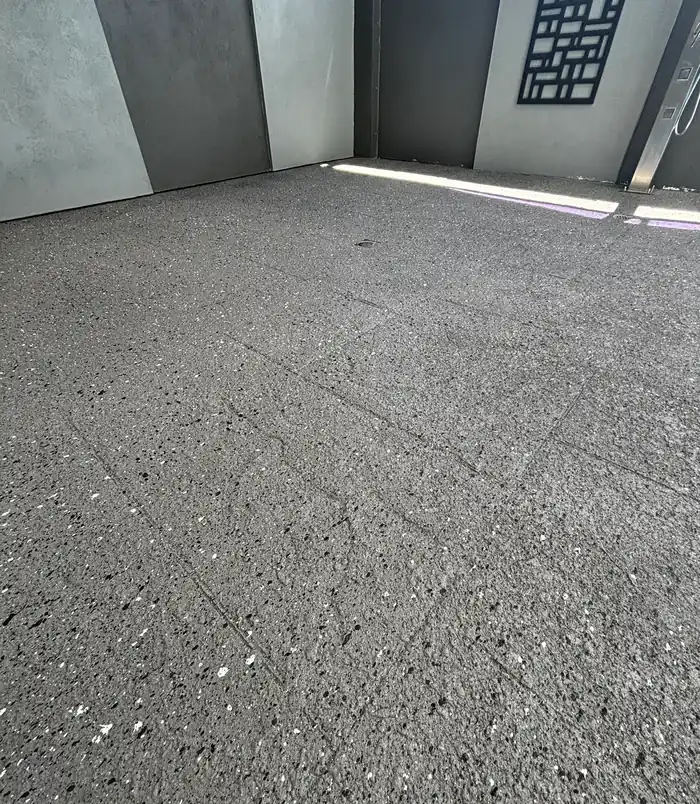 Smooth speckled grey resurfaced concrete floor beside a rendered wall