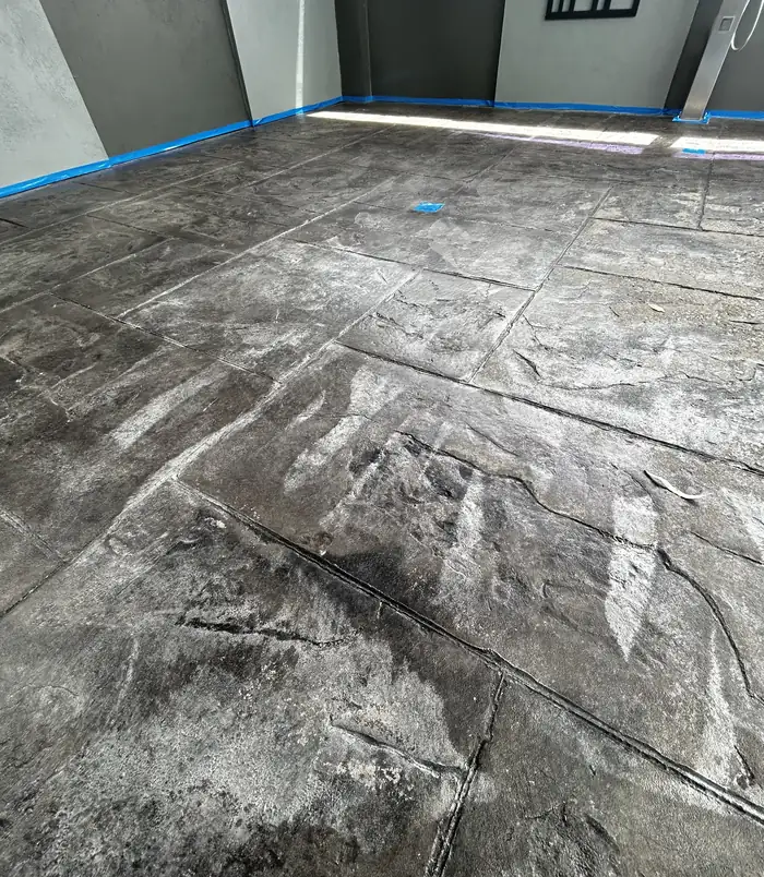Worn concrete surface dusted with grinding residue and blue masking tape, before resurfacing