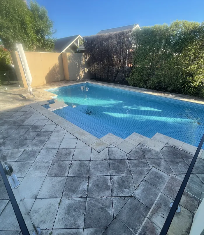 Dirty, discoloured pool surround and steps beside a swimming pool, before pressure washing