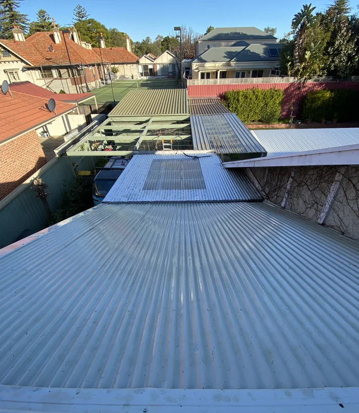 Clean corrugated roof sheeting beside a pergola, free of moss and debris after pressure washing