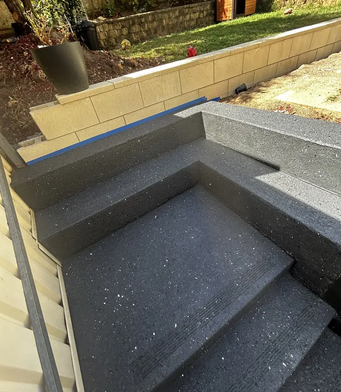 Speckled grey resurfaced concrete steps beside a retaining wall