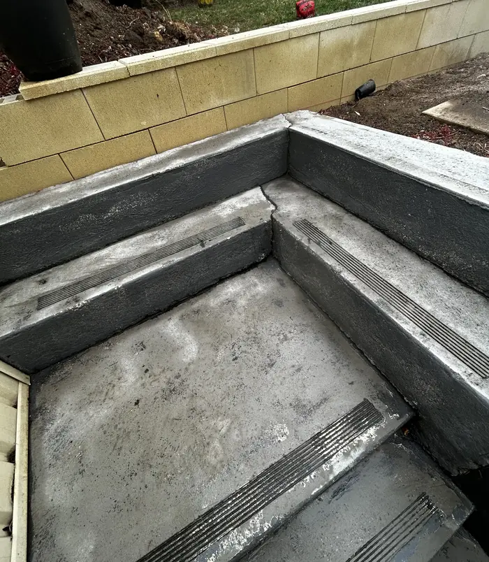 Worn, stained concrete steps beside a retaining wall, before concrete resurfacing
