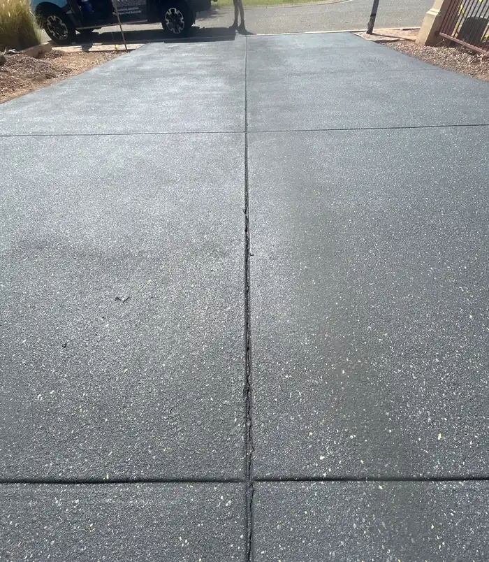 Smooth blue-grey resurfaced concrete driveway leading to the street