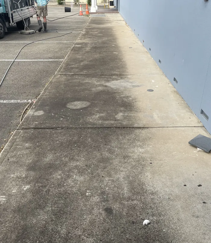 Grimy, discoloured concrete path beside a house wall, before pressure washing